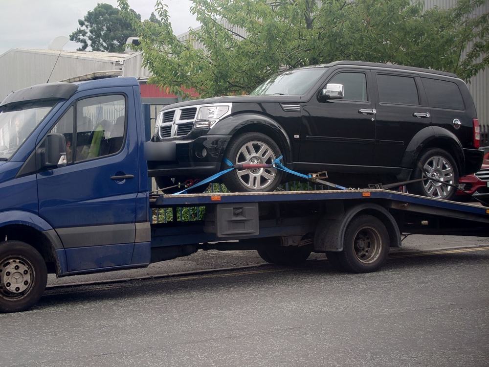 Black 4x4 secured on a recovery truck